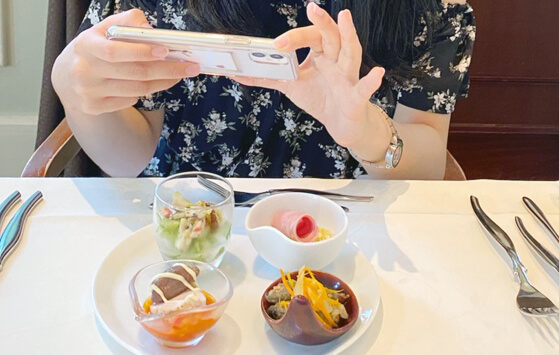 若い人が飲食店内でインスタ映えしそうな料理を スマホで写真を撮っている